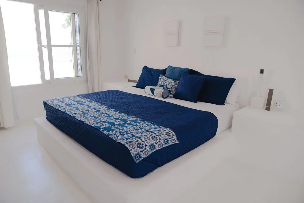 Cama azul y dos relieves blancos en la pared.