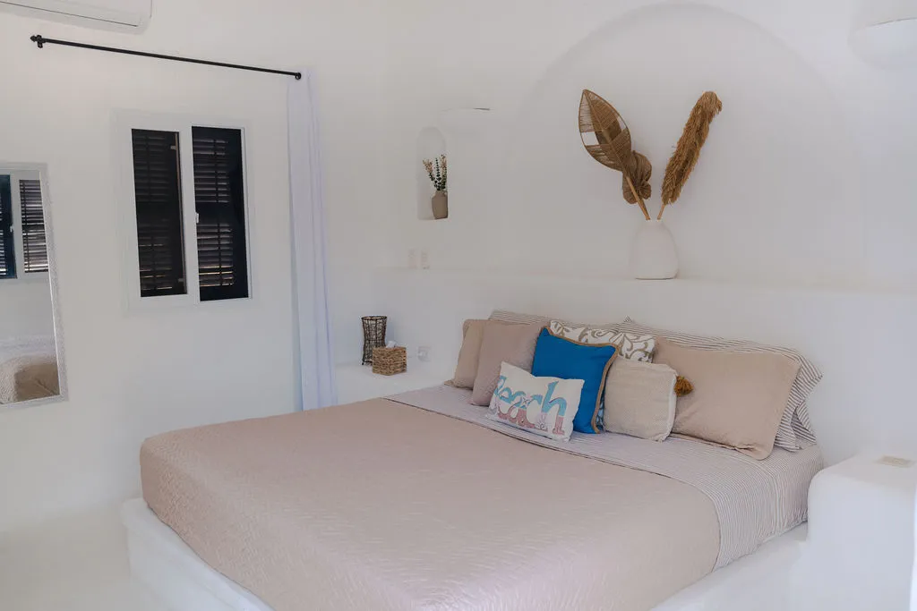 Cama beige y decoración de hojas sobre la cabecera.