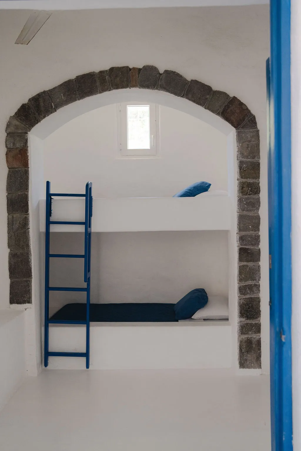 Camarote con escalera azul dentro de un arco de piedra.