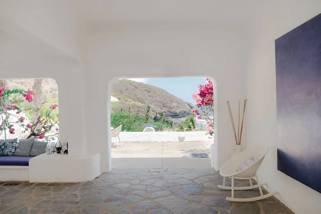 Sala abierta con arcos blancos y vista hacia la costa.